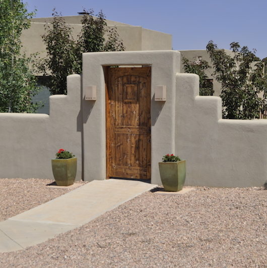 Stucco wall enclosing a courtyard. Made by Serrano Landscape.